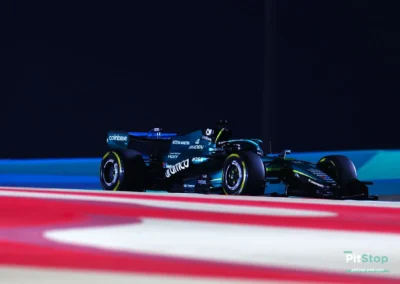 Lance Stroll en piste de nuit avec l'Aston Martin AMR26 à Bahreïn, éclairage artificiel soulignant la livrée vert satiné.