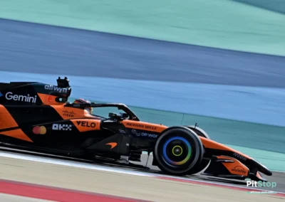 Gros plan de profil sur la McLaren MCL40 d'Oscar Piastri en mouvement sur le circuit de Sakhir, montrant les détails de l'aileron avant et du cockpit.