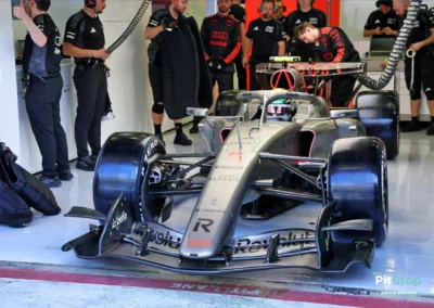 La monoplace Audi R26 de Gabriel Bortoleto dans son garage à Bahreïn, entourée des mécaniciens de l'équipe.